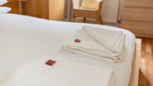 A neatly made bed with folded white linens and a small red tag on the pillow. - Silver Lining - Grassmarket Apartments (Edinburgh)