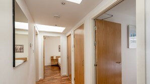 A hallway with wooden flooring, a skylight, and a door leading to a bedroom. - Silver Lining - Grassmarket Apartments (Edinburgh)