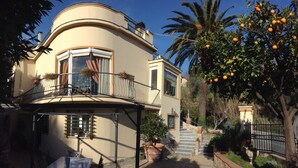 A two-story house with a balcony, a staircase leading to the upper floor, and a tree with oranges. - Villa Sofia: apartments for short term holidays. (Lerici)