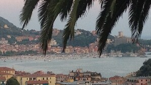 A coastal town with buildings along the waterfront, a view of the sea, and palm trees in the foreground. - Villa Sofia: apartments for short term holidays. (Lerici)