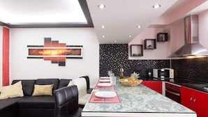 A modern kitchen with a central island, red cabinetry, and a black backsplash.