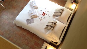 A neatly made bed with white linens, striped pillows, and a small card on the bed. - L'Isolo Bed and Breakfast (Monzambano)