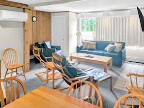 A furnished living room with a sofa, chairs, a coffee table, and a TV.
