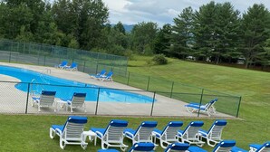 Ein Swimmingpool mit blau-weißen Liegestühlen darum herum.