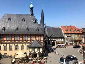 A traditional European town square with historic buildings, a clock tower, and outdoor seating areas. - Maisonette at the market Castle view | WLAN + Netflix (Wernigerode)