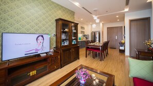 A modern living room with a TV, wooden cabinet, dining table, and chairs. - Luxury Apartment Vinhomes Metropolis 02 BR#5**Sky View# (Hà Nội)