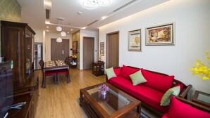 A modern living room with a red sofa, wooden dining table, and a glass coffee table. - Luxury Apartment Vinhomes Metropolis 02 BR#5**Sky View# (Hà Nội)