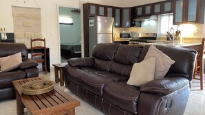 A living room with a leather sofa, wooden coffee table, and a wall-mounted macrame piece. - Luxury Poolside Apartment. Your Serene Getaway Awaits! (El Pajonal)