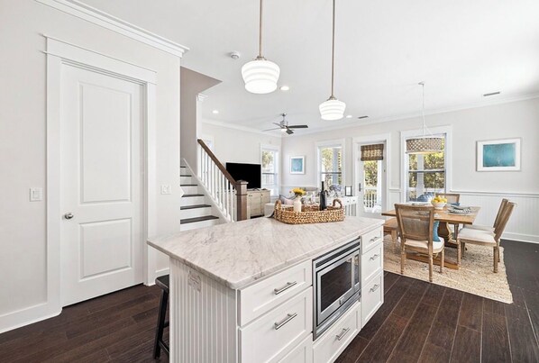 A spacious kitchen with a marble island, white cabinetry, and a dining area with a wooden table and chairs.