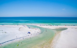 A beach with clear turquoise waters, sandy shores, and several umbrellas and beach chairs.