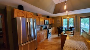 A modern kitchen with stainless steel appliances, wooden cabinets, and a granite countertop. - Sunset Cove Eagle River- Waterfront Retreat on Catfish Lake (Eagle River)