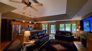 A modern living room with a black leather sofa, a coffee table, and a television mounted on the wall. - Sunset Cove Eagle River- Waterfront Retreat on Catfish Lake (Eagle River)