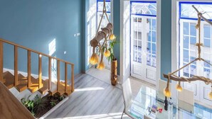 Un intérieur moderne avec un escalier en bois, un luminaire suspendu et une table en verre sur laquelle se trouve une bouteille.