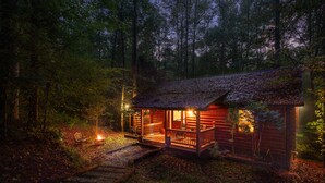 A rustic cabin with a porch, a fire pit, and a small deck.