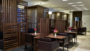 A restaurant with wooden partitions, tables with chairs, and flower centerpieces. - Naya (Algiers)