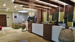 A reception area with a modern design, featuring a reception desk, a large vase, and a chandelier. - Naya (Algiers)