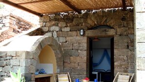 Un edificio in pietra con un portale ad arco, un piccolo tavolo con sedie e una pianta in vaso.