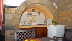 Un arco in pietra conduce a una cucina con schienale piastrellato, piano cottura a gas e frigorifero.
