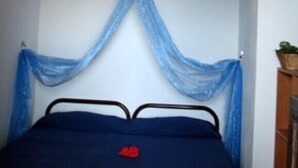 Una camera da letto con un letto, una lampada a sospensione e una testiera drappeggiata di blu.