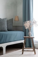 Un dormitorio con una cama, una mesita de noche con un jarrón de flores y una lámpara colgante.