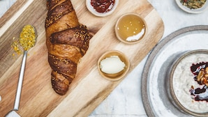 A wooden board with a croissant, two small bowls of jam, and a spoon. - Hoy Paris - Home of YOGA (Paris)