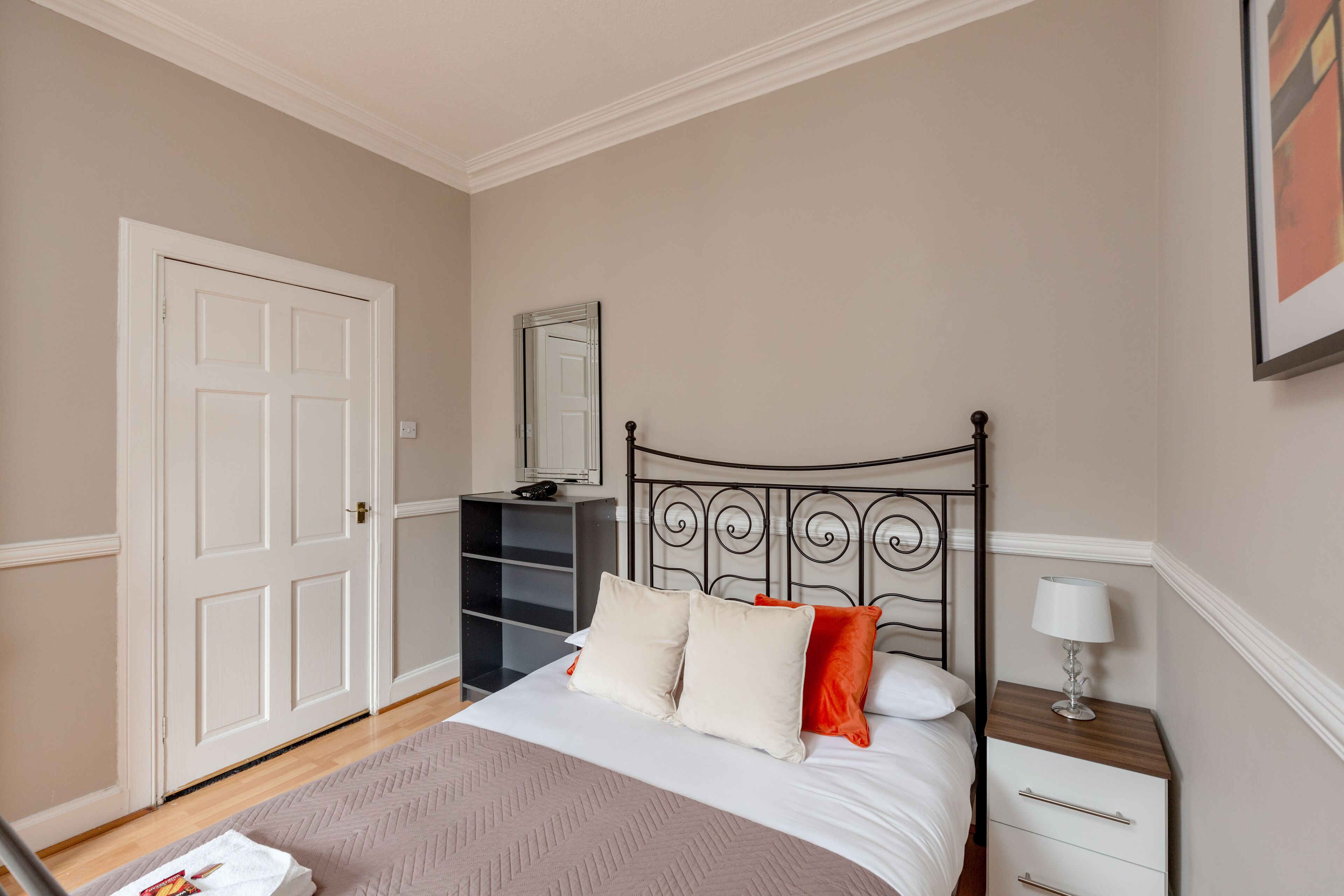 A bedroom with a bed, bedside table, and a wardrobe.