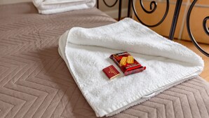 A neatly made bed with a white towel and a box of Walker's Shortbread biscuits. - Silver Lining - St Leonard St Apartment (Edinburgh)