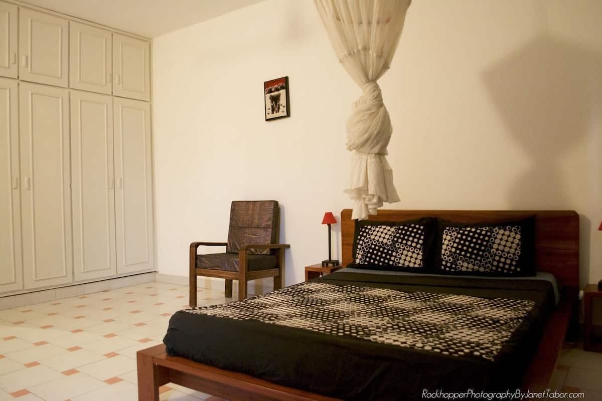 Ein Schlafzimmer mit Bett, Stuhl, Kleiderschrank und einem an der Wand hängenden Bild.