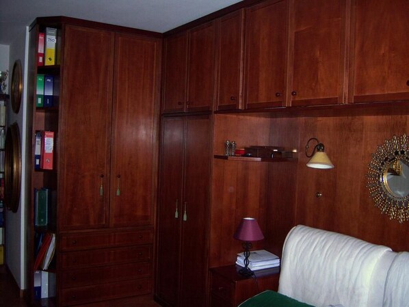 A room with wooden cabinets, a green sofa, a lamp, and a mirror on the wall. - Talenti house (Roma)
