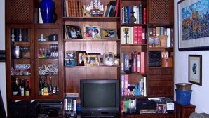 A living room with a wooden entertainment center, shelves with books and decorative items, a television, and a framed painting on the wall. - Talenti house (Roma)