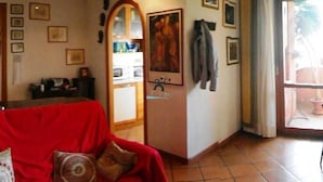 A living room with a red sofa, a mirror, and a door leading to a kitchen. - Talenti house (Roma)