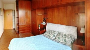 A bedroom with a large bed, wooden wardrobe, and a nightstand with a lamp. - Talenti house (Roma)