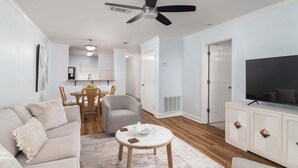 A living room with a sofa, chairs, a coffee table, a TV, and a ceiling fan.