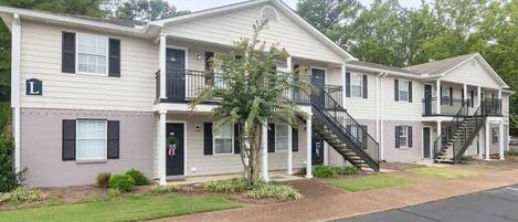 A two-story motel with a covered porch, a small tree, and a staircase leading to the upper level.