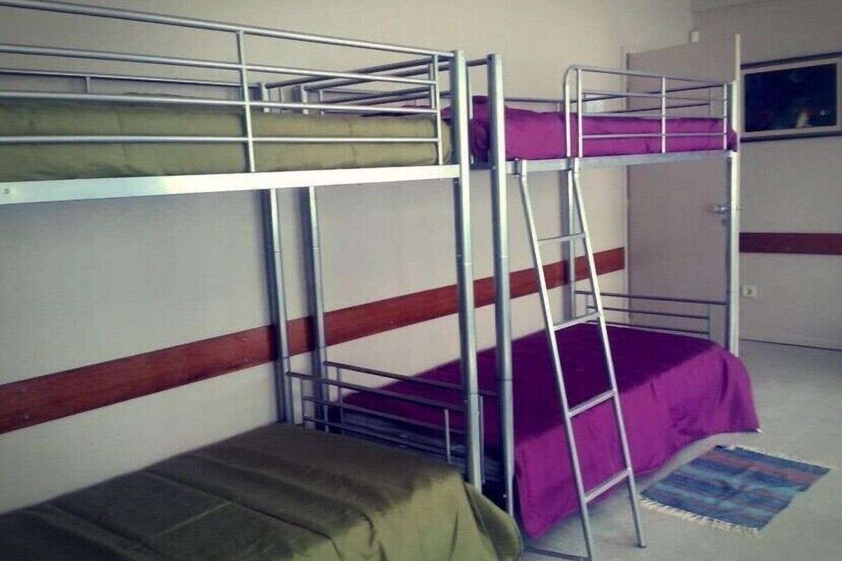 A bunk bed room with a window, a door, and a small rug.