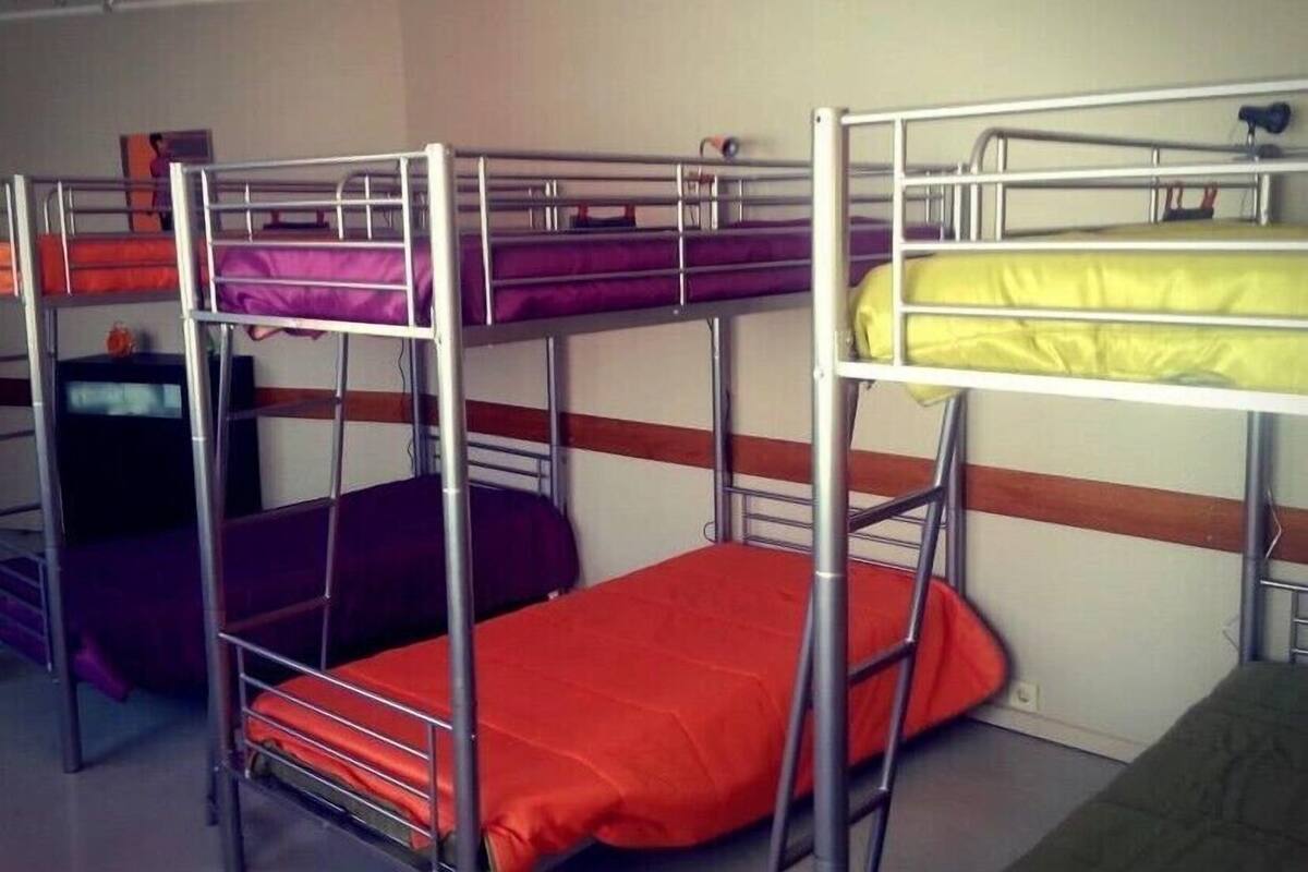 A dormitory room with bunk beds in various colors.