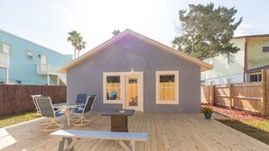 A house with a deck, a dining table with chairs, and a small patio area.