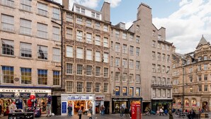 A street view of Edinburgh's historic buildings with shops and a red telephone box. - Silver Lining - Luxury Jackson Apartment (Edinburgh)