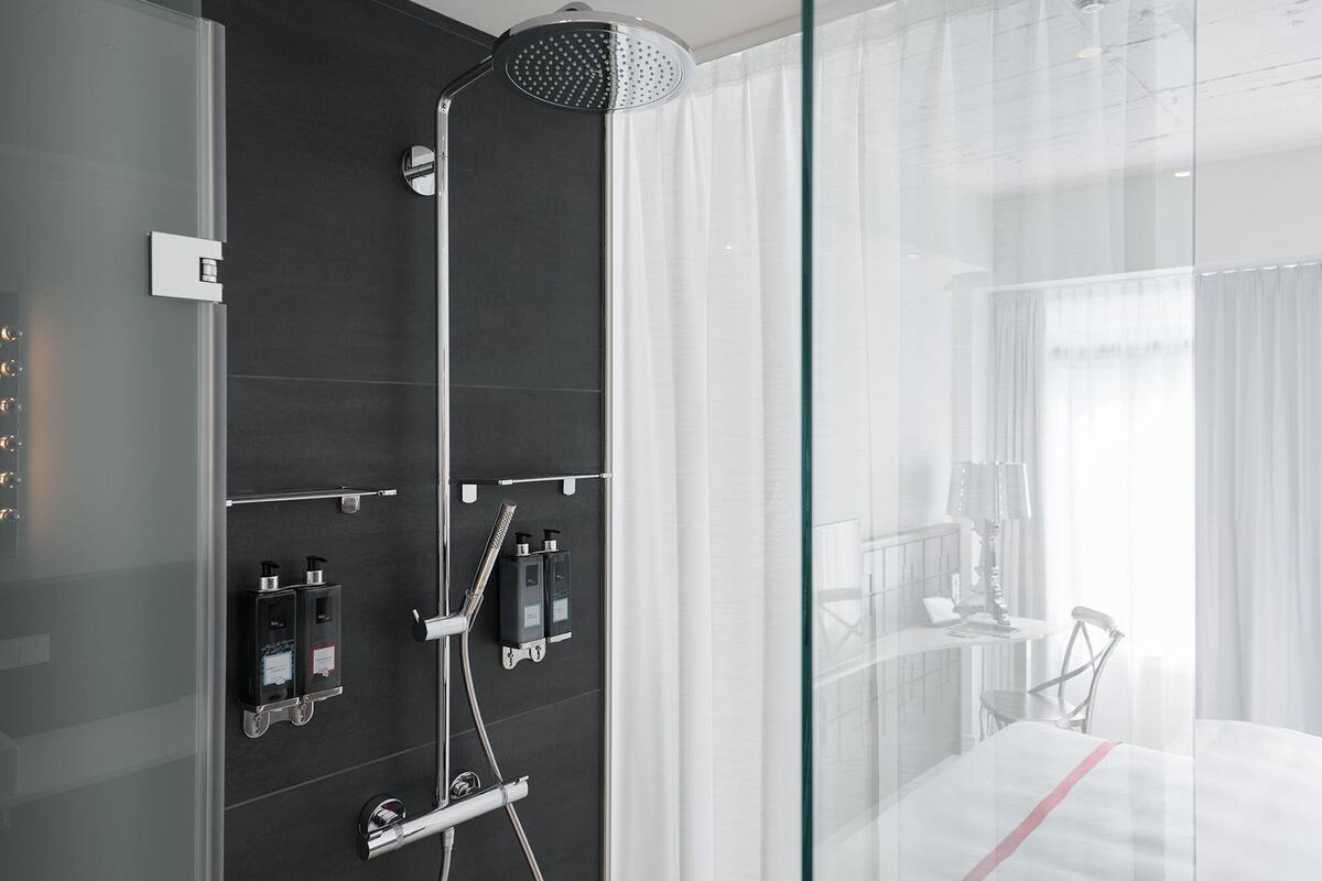Ein modernes Badezimmer mit Duschkabine aus Glas, einer Bedienkonsole und einem Nachttisch mit Stuhl.