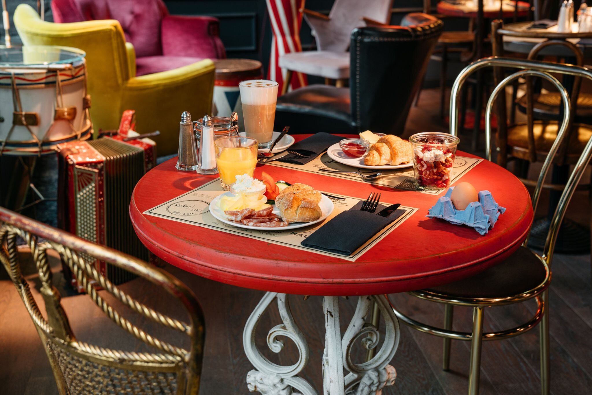 A dining table with breakfast items, a glass of orange juice, and a menu.