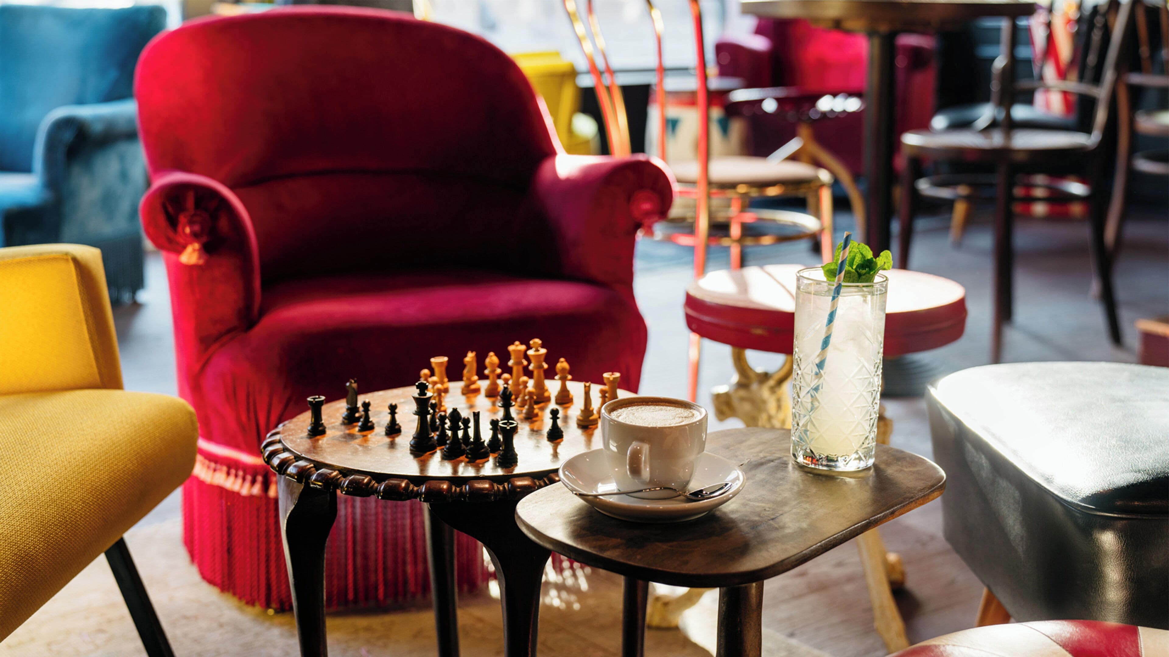 A chessboard on a table with a cup and a glass of water.
