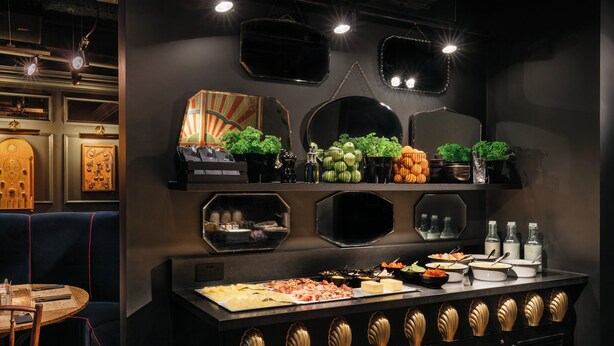 A buffet setup with various food items and a seating area with a table and chairs.