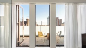 A room with a sliding glass door leading to an outdoor patio with two chairs and a small table. - Ruby Lucy Hotel London by IHG (London)
