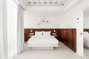 A modern bedroom with a central bed, wooden headboard, and a decorative wall piece. - Ruby Lucy Hotel London by IHG (London)