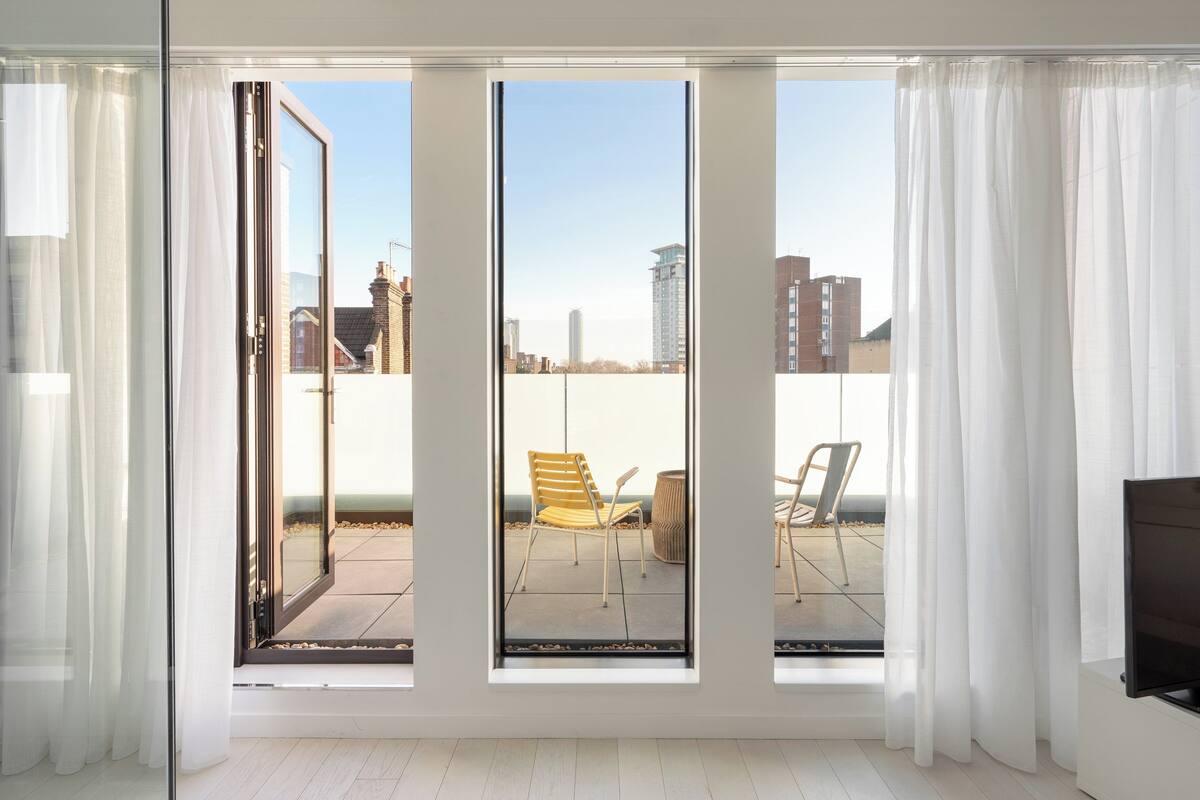 Ein Zimmer mit großen Fenstern, einer Schiebetür und Blick auf die Stadtlandschaft.