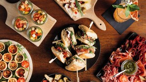 A variety of food items including sandwiches, charcuterie, and appetizers on a wooden table.