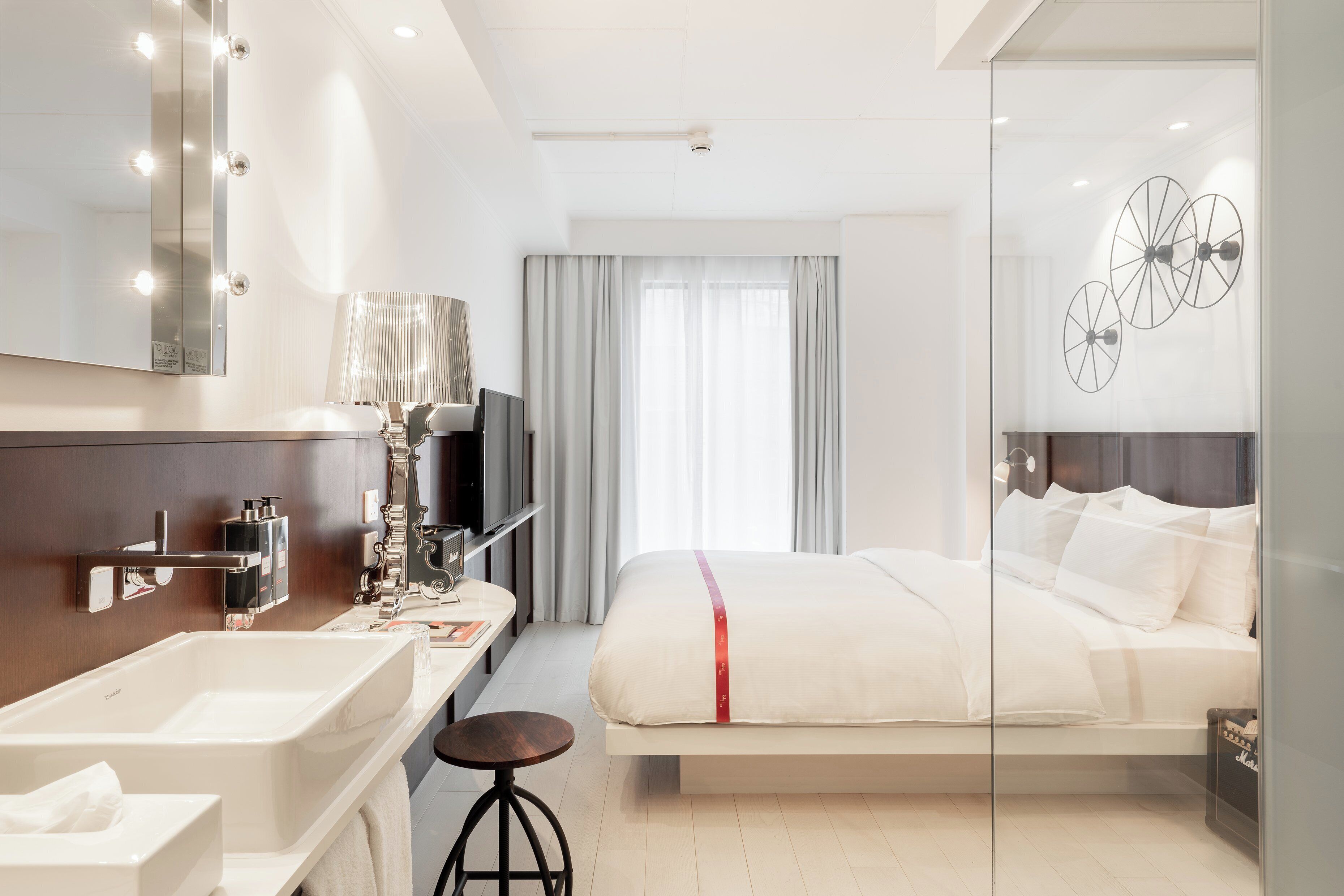 A modern hotel room with a large bed, a vanity with a mirror, and a television.
