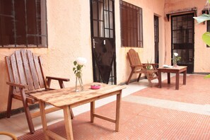 A wooden table and chairs set on a tiled floor with a window and door in the background. - Ouaka Hotel (Ouagadougou)