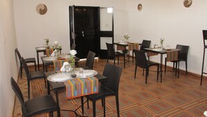 A dining area with tables set for four, black chairs, and a patterned carpet. - Ouaka Hotel (Ouagadougou)