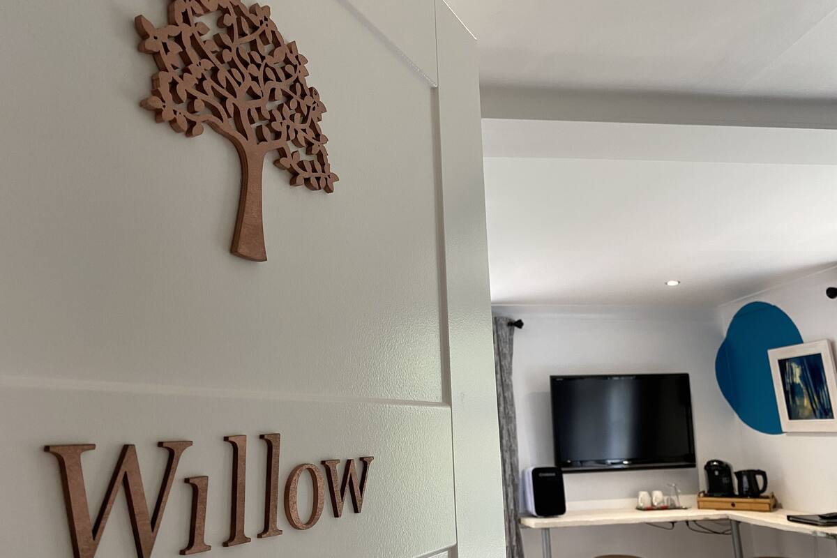 En modern inredning med en träpanel på väggen som föreställer ett träd, och ordet ”Willow” placerat under trädet.